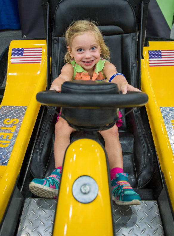 Sophia Owens, of Louisville, plays in a go-kart while touring the South Wing of the Expo Center at the Kentucky State Fair. Photo by Bobby Ellis, Aug. 24, 2017