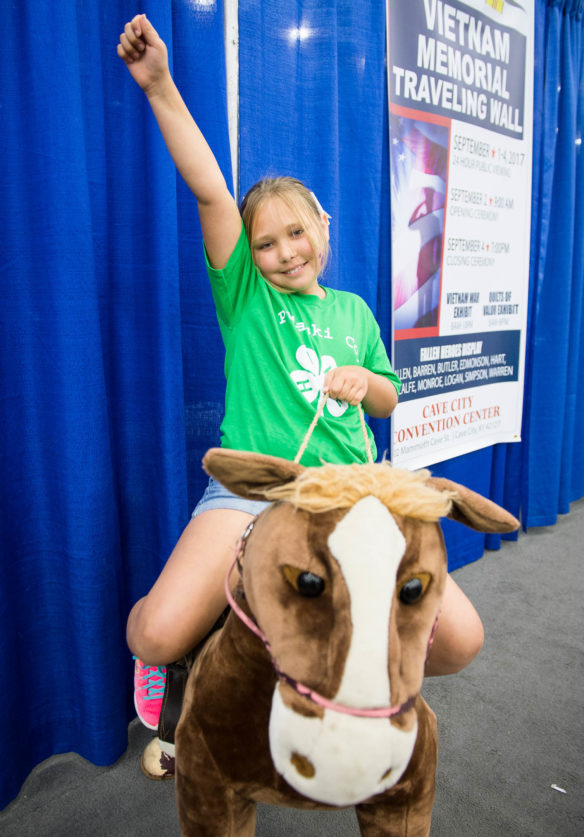 Kaylee Corder, a student at Northern Middle School (Pulaski County) rides a stuffed horse in the south wing of the Expo Center at the Kentucky State Fair. Photo by Bobby Ellis, Aug. 24, 2017