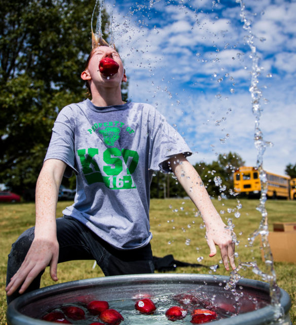 Priscilla Godfrey, a 9th-grader at KSD, pulls an apple out of the tub while bobbing for apples. Photo by Bobby Ellis, Oct. 6, 2017