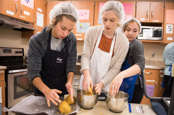 Madeline Borders, left, Kara Greenwell, center, and Mary Hughes roll ice cream balls in corn flakes while making fried ice cream in Sarah Raikes' foods class at Washington County High School. Washington County High's principal estimated that about 90 percent of the school's students take at least one family and consumer sciences course. Photo by Bobby Ellis, Oct. 17, 2017