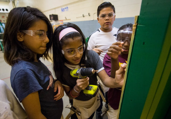 Enas Rahim, left, and Sandhya Upreti use a power drill to screw a prefabricated wall to the frame of a house during the Hammering Home Math program. Photo by Bobby Ellis, Oct. 19, 2017