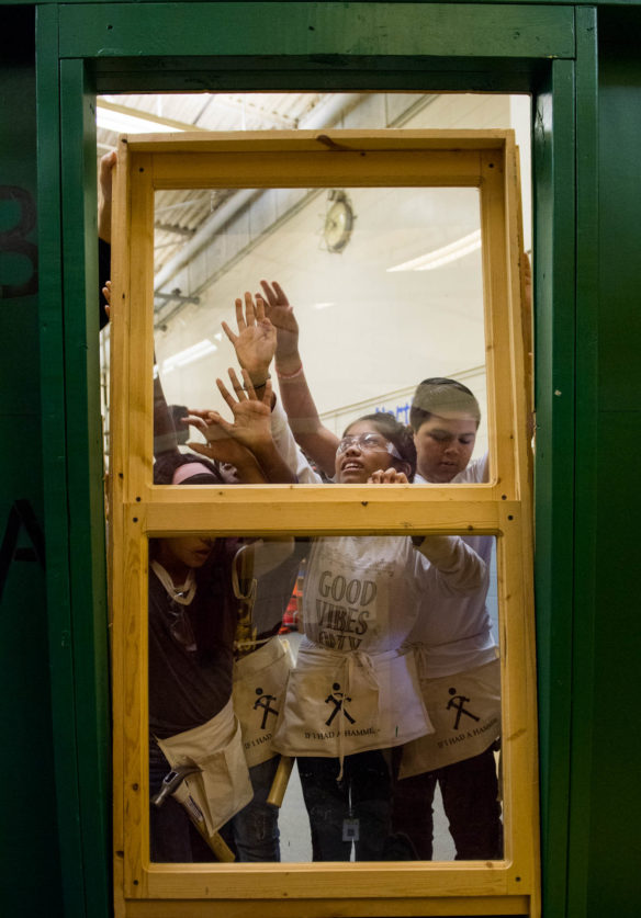 Alondra Reyes, a 5th-grader at Lansdowne Elementary (Fayette County), center, helps put a window in place on a pre-built home used in the "Hammering Home Math" program. Photo by Bobby Ellis, Oct. 19, 2017