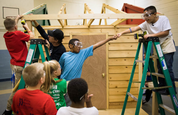 Jerris Scott, left, fist bumps Trejan Happy as they help build a house with their classmates. Photo by Bobby Ellis, Oct. 19, 2017