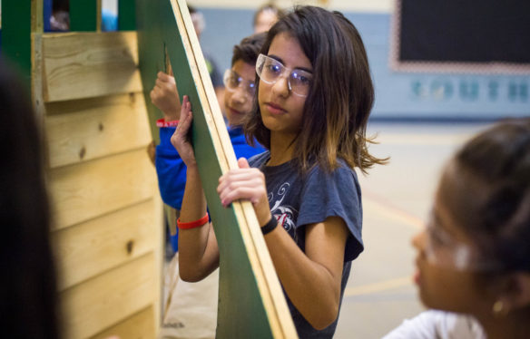 Enas Rahim, a 5th-grader at Lansdowne Elementary, helps to carry siding for the house that she and her classmates worked to build. Photo by Bobby Ellis, Oct. 19, 2017