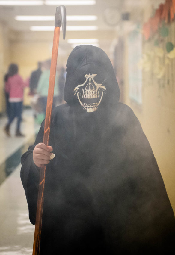 Parker Ishmael, a 4th-grader at Northside Elementary, walks through a cloud of fog dressed as the Grim Reaper at the school's annual fall festival. Photo by Bobby Ellis, Oct. 27, 2017