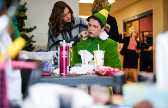 Carlee Cornett, the music teacher at Lincoln County Middle School, left, helps Holden Stamper, 8th-grade, playing Buddy the Elf, tape his microphone to his face backstage. Photo by Bobby Ellis, Dec. 8, 2017