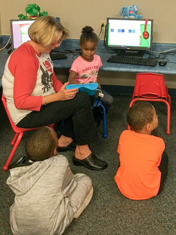 Henderson County district substitute and retired educator Brucie Farris teaches a class at the Thelma B. Johnson Early Learning Center to code using Daisy Dino on the iPad in the library. Even though school librarian Rhea Isenberg thought her practices were engaging and progressive, she discovered she could be doing more after she started trying to obtain her National Board certification. Submitted photo by Rhea Isenberg