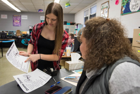 Victoria Vela, a freshman at Harrison County Area Technology Center, shows teacher Amber Florence a poster for her drone instruction service. Florence teaches eight courses in the school's business pathway, all of which are dual-creit courses. Photo by Bobby Ellis, Dec. 5, 2017
