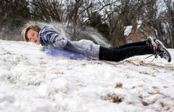 Dawson Pearl, a 7th-grader at Second Street School (Frankfort Independent) rides a sled down a hill behind the Capitol Annex in Frankfort. Photo by Bobby Ellis, Jan. 13, 2018