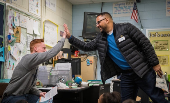 Christian Adair, the head of the R.E.A.L. Men Read program, right, gives a high five to Kyle Hancock, a community partner, before he reads a book to Buckley Hancock's, his wife, 2nd-grade class at Lansdowne Elementary (Fayette County). Photo by Bobby Ellis, Jan. 24, 2018