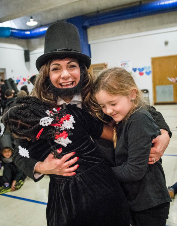 Susan French-Epps, the principal of Lincoln Elementary, hugs a student after the school unofficially set a record for the most people dressed as Abraham Lincoln in the same place. Photo by Bobby Ellis, Feb. 14, 2018