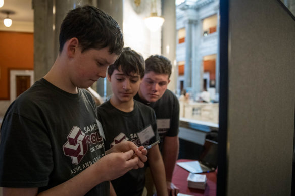 Isaac Campbell, an 8th-grader at Ashland Middle School, sets out a needle to demonstrate how the device AMS students created works. Photo by Bobby Ellis, March 6, 2018