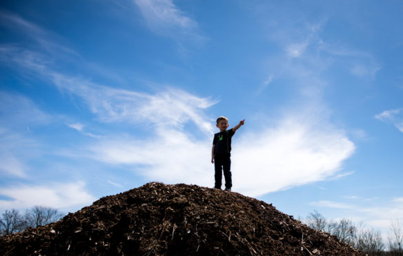 Jackson Middleton stands on a woodpile and points to the machines at the Big Dig. Photo by Bobby Ellis, April 21, 2018