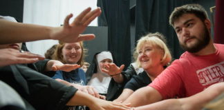 Frieda Gebert, the drama teacher at Boyle County High School, has the cast of "Sister Act" come together before the final performance at the Ragged Edge Theater in Harrodsburg. The school has to rent the theater because it does not have a performance space. Photo by Bobby Ellis, May 12, 2018