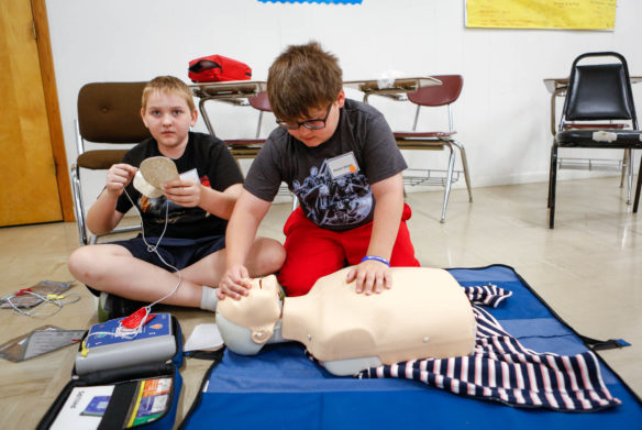 Preston Moore, right, a 7th-grade student at Robertson County Middle School, practices CPR technique as classmate Ephraim Hughes prepares to attach an automated external defibrillator to the dummy during the nontraditional camp at Mason County Area Technology Center. Boys at the camp learned first aid skills and completed a lifesaving course, while girls rotated among the school's four traditionally male-dominated program areas. Photo by Mike Marsee, May 30, 2018