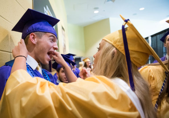 Tanner Clos, left, has his hat adjusted by his sister, Taylor Clos before the start of the graduation ceremony. Photo by Bobby Ellis, June 4, 2018