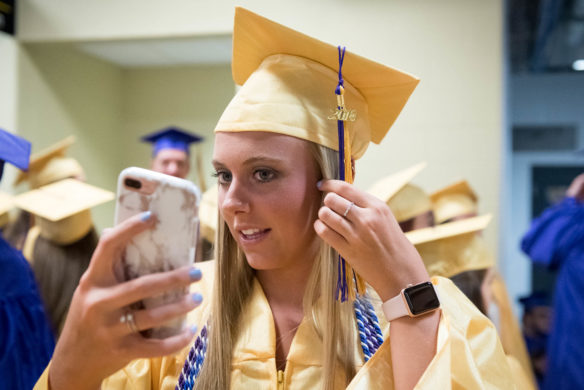 Kylie Reachen uses her cell phone to adjust her hair before the start of the ceremony. Photo by Bobby Ellis, June 4, 2018