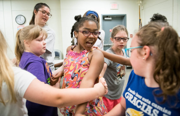 Yasmine Legendre plays a game of the Group Knot, a game where teams create a knot with their arms and must untie themselves without letting go of each other's hands, as part of a critical thinking exercise at the STEM You Can! camp. Photo by Bobby Ellis, June 13, 2018