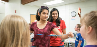 Arushi Gupta, left, and Sanjana Kothari hand out yarn as STEM You Can! goers make a food web in a game where they decide whether a certain organism is either a producer or consumer. Photo by Bobby Ellis, June 13, 2018