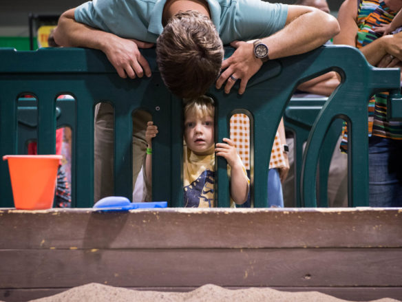 Phillip Overall looks at his son, Parker Overall through a plastic barricade as Parker waits to dig in a fossil pit at the Jurassic Quest event. Photo by Bobby Ellis, July 6, 2018