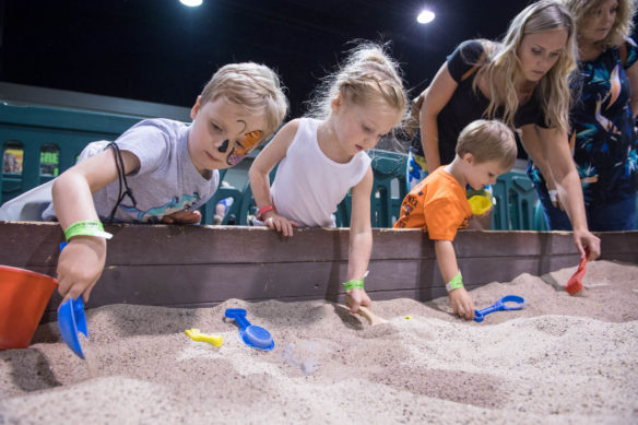 Children dig in a fossil pit during Jurassic Quest. The event, which was held in Rupp Arena, is a traveling fair that lets children ride animatronic dinosaurs, search for fossils and walk through an educational replica of an ancient forest. Photo by Bobby Ellis, July 6, 2018
