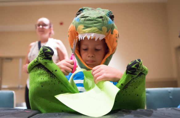 Seth Ferguson cuts out a paper dinosaur at an arts and craft table at the Jurassic Quest event. Photo by Bobby Ellis, July 6, 2018