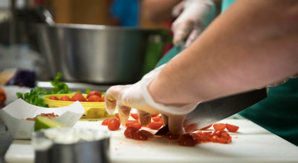 Cherry tomatoes are chopped up during the lab portion of a hands on summer training session for school nutrition professionals put on by the Kentucky of Education in partnership with the Institute of Child Nutrition at Henry County Middle School. Photo by Bobby Ellis, Aug. 1, 2018