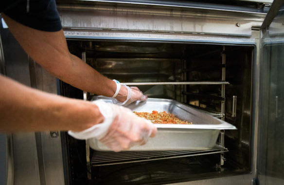 Barbara Burkhardt, a cook at Trimble County Elementary School, puts food into an oven to cook. Photo by Bobby Ellis, Aug. 1, 2018