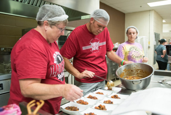 Joey Parks, center, spoons out beans and corn during the nutritional training lab. Photo by Bobby Ellis, Aug. 1, 2018