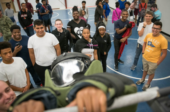 Abdullahi Otun, a student at the Academy at Shawnee (Jefferson County) attempts to do a pull-up while wearing a bomb disposal suit during a Navy visit to the NJROTC program. Photo by Bobby Ellis, Aug. 23, 2018