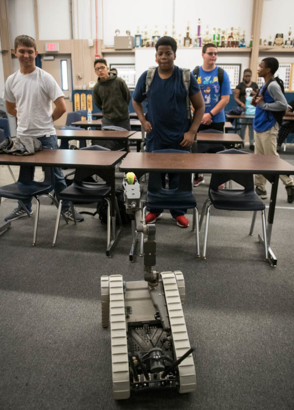 NJROTC students watch as a robot used by EOD techs drives around their classroom during a Navy visit. Photo by Bobby Ellis, Aug. 23, 2018