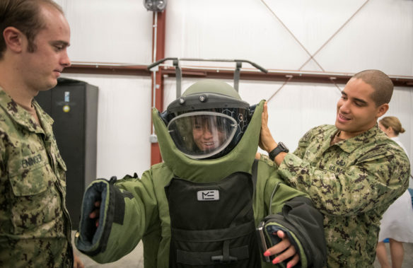 Gueneverie Diffenbacher, an 11th-grader at the Academy at Shawnee (Jefferson County), is helped into a bomb suit by EOD2 Abraham Ruic. Photo by Bobby Ellis, Aug. 23, 2018