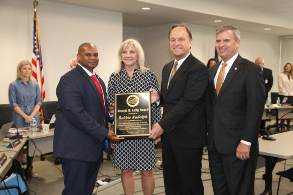 The 18th annual Joseph W. Kelly Award was presented to Robbie Rudolph, second from right, president of Rudolph’s Inc. and founder of Four Rivers Foundation, at the Kentucky Board of Education meeting today in Frankfort. Presenting the award is, from left, Interim Education Commissioner Wayne Lewis, Lisa Rudolph and Board Chairman Hal Heiner, right. Photo by Megan Gross, Oct. 2, 2018.