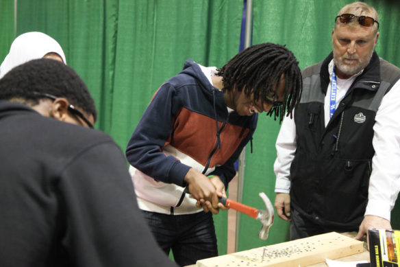 Seyvion Mogorosi of Tates Creek High School races to be the first of his friends to sink a nail into a piece of wood. They were visiting a booth to show students possible careers in the field of construction during the 2nd annual Academies of Lexington Career Expo. Photo by Megan Gross, Nov. 5, 2018