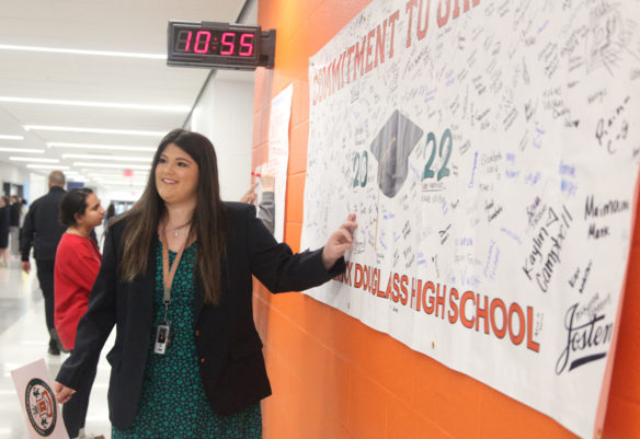 Shelby Frazier, the senior class president at Frederick Douglass High School (Fayette County), shows visitors to the school a banner signed by members of the current freshman class as part of a commitment to graduation ceremony that will be displayed at their graduation in 2022. Freshmen at the three schools that are part of the Academies of Lexington are in their own academies that offer personal and career exploration and serve to help students make the transition from middle school to high school. Photo by Megan Gross, Dec. 3, 2018