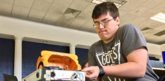 Bryan Grant, a student of Brian Barrett at Ohio County High School, cleans contacts and checks fuses in the computer that run Buster the School Bus. Several of Barrett's classes used the broken remote-controlled robot to get a hands-on lesson about how to repair aging technology. Submitted photo by the Ohio County High School yearbook staff