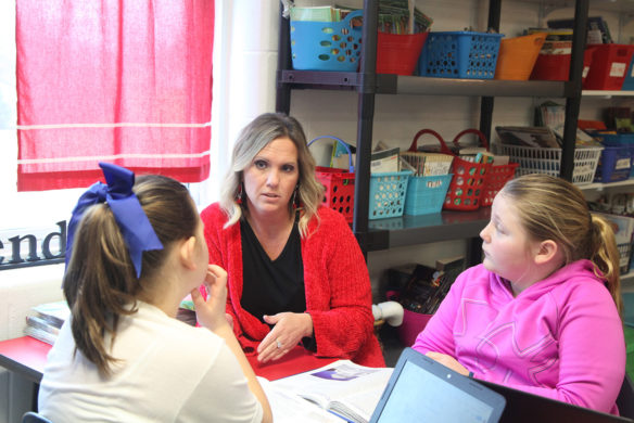 Angie Beavin talks with two students in her 5th-grade classroom at Peaks Mill Elementary School (Franklin County). Beavin said she prefers talking to students eye to eye rather than from the front of the classroom because they are more likely to hone in on what she is telling them. Photo by Megan Gross, Feb. 11, 2019
