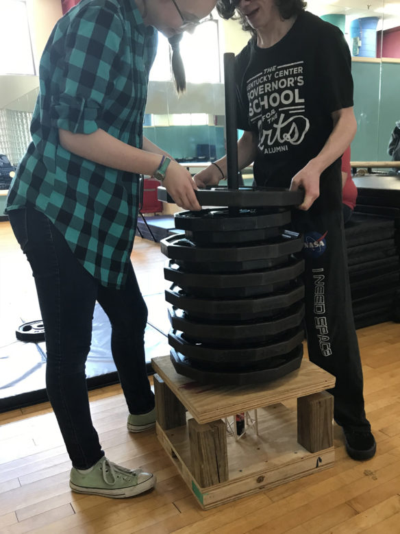 Kiera Risner and Caleb Middleton of the Corbin High School structure team test their 8-inch, 15-gram structure to see how much weight it can hold. Photo submitted