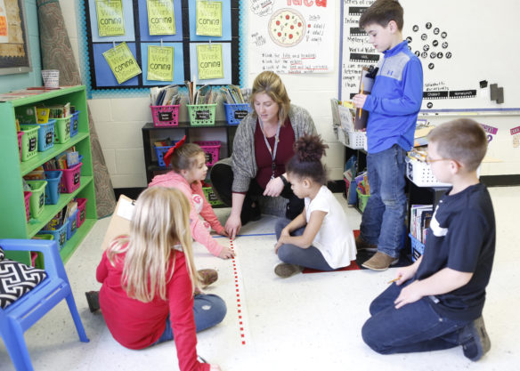 Abby Hill, a special education teacher at Junction City Elementary School (Boyle County), shows a group of 2nd-grade students how to measure the distance of a student’s leap. Special education teachers who might once have been in general education classrooms only in a support role are teaching alongside general education teachers in shared learning classrooms. Photo by Mike Marsee, Feb. 14, 2019