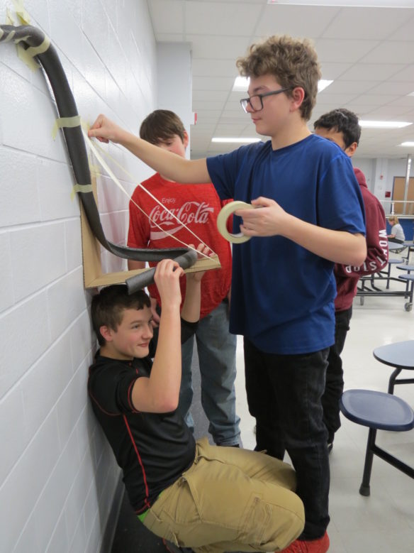 North Bullitt High School students, from left, Chase Talbott (kneeling under the roller coaster), Brandon Bowles and Alex Rightsell test out their roller coaster track during the district's annual STEM competition. The middle and high school student teams in Bullitt County had to construct a roller coaster in less than two hours using specific materials and without parental assistance. Photo submitted