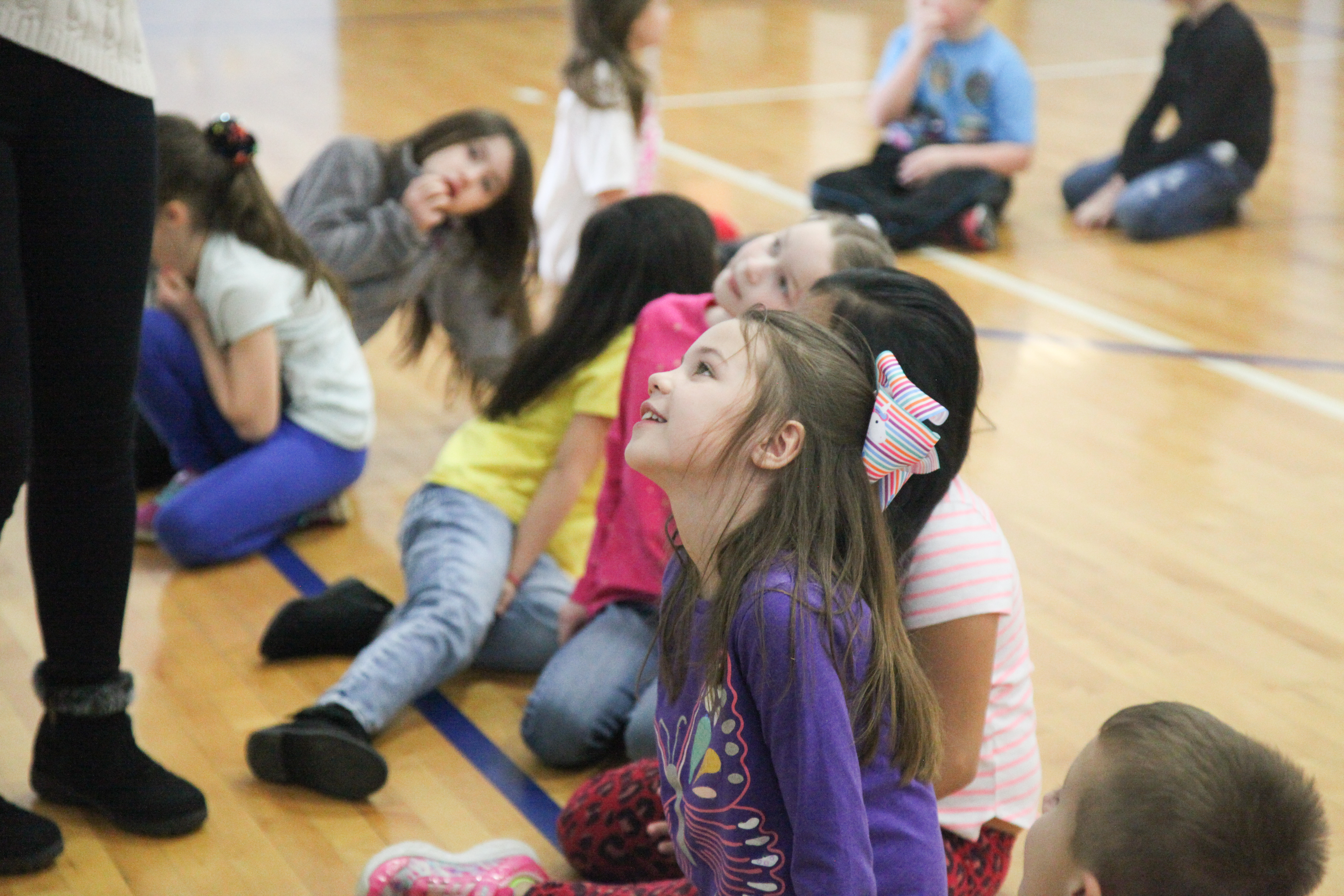 At Huntertown, teachers cultivate positive relationships in every learning setting. Third-grader Lila Slade, center, and her classmates focus on learning while taking a memory moment during Chinese lessons in physical education class.The students watch their Chinese teacher act out different actions while they say what she is doing in Chinese. Photo by Megan Gross, March 14, 2019