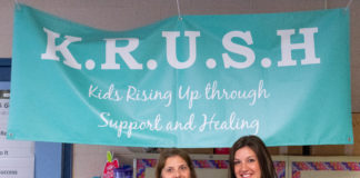 Kristi Whittaker, left, and Jalina Wheeler stand in front of a sign for the Kids Rising Up through Support and Healing (KRUSH) program.