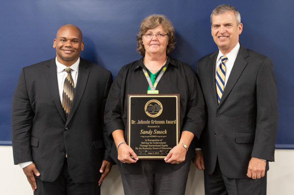 At its meeting June 5, Education Commissioner Wayne Lewis, left, and Kentucky Board of Education Chair Hal Heiner presented Sandy Smock with the eighth annual Dr. Johnnie Grissom Award.