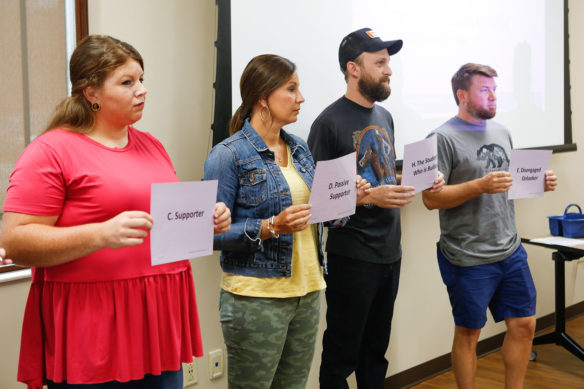 Members of the Montgomery County schools’ Olweus bullying prevention coordinating committee assume the roles of a student who is being bullied and others who support the action or allow it to continue as part of an exercise during their training. Photo by Mike Marsee, Aug. 1, 2019
