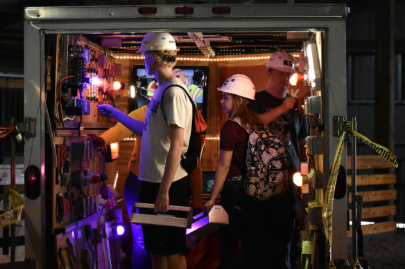 A group of students gather into a vehicle that has been equipped with various electrical switches.