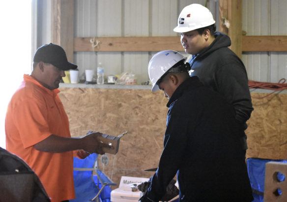 Bobby Cunningham (from left) from Masonry Additions demonstrates the proper way to lay brick to Michael Ixcoy and Hunter Van, both from Martha Layne Collins High School (Shelby County).