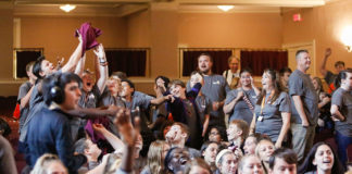 Aaron Meadows, center, a 7th- and 8th-grade history teacher at Paris Middle School (Paris Independent) watches as his students vie for T-shirts being thrown into the crowd at a kickoff celebration for GEAR UP Kentucky at Eastern Kentucky University in Richmond. Photo by Mike Marsee, Sept. 25, 2019