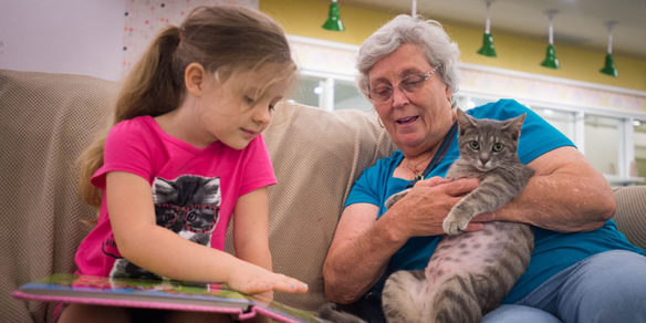 A child reads to her grandmother, who is holding a cat, at the Ashland Mall in 2016.