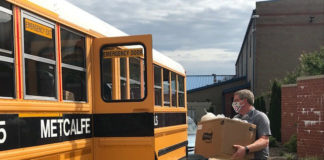 Josh Hurt loads packaged food as meals for students onto buses amid the COVID-19 pandemic.