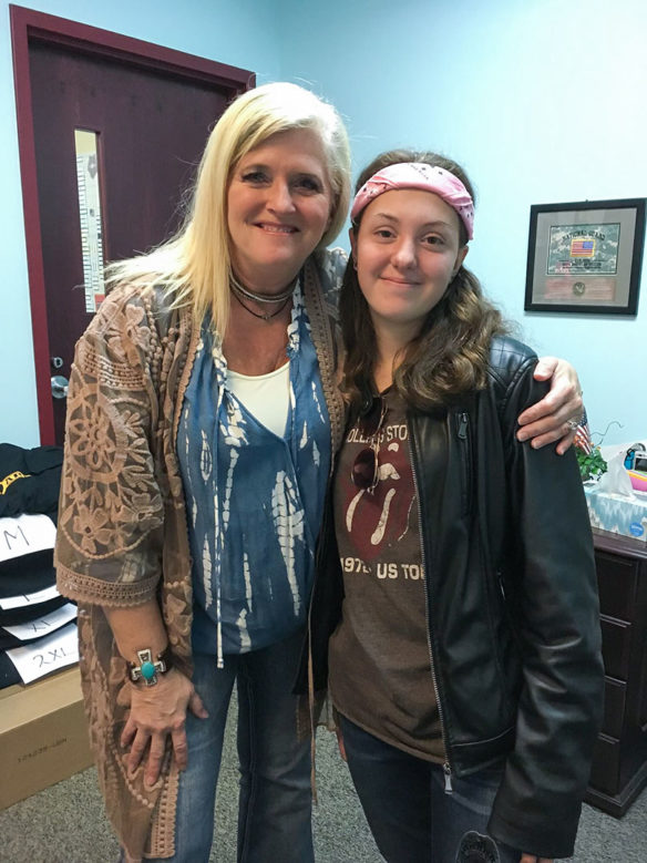 A woman stands next to a student with her arm around the girl's shoulder.